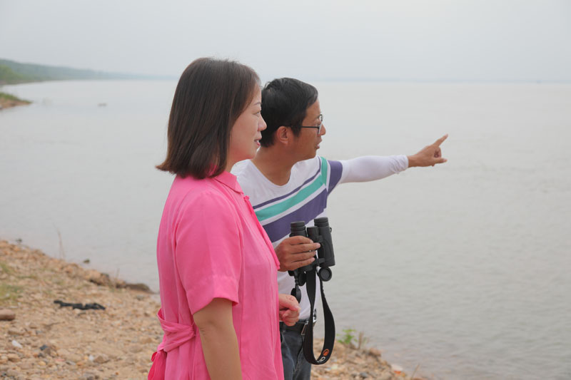 自愿者徐建利（右），，，，，向王琼解说江豚拍摄点位和寓目角度。。。。。。h49a1727.jpg